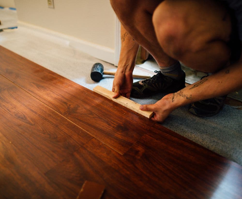 Flooring installer fitting hardwood planks