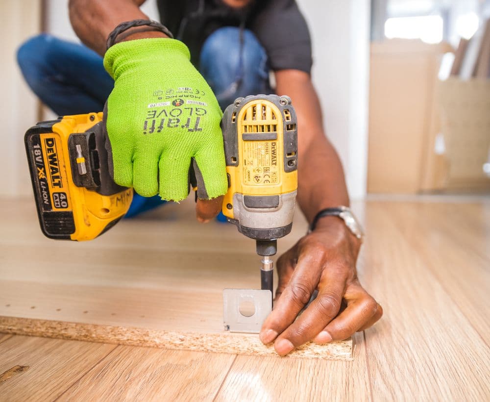 Installer fastening flooring with a power drill
